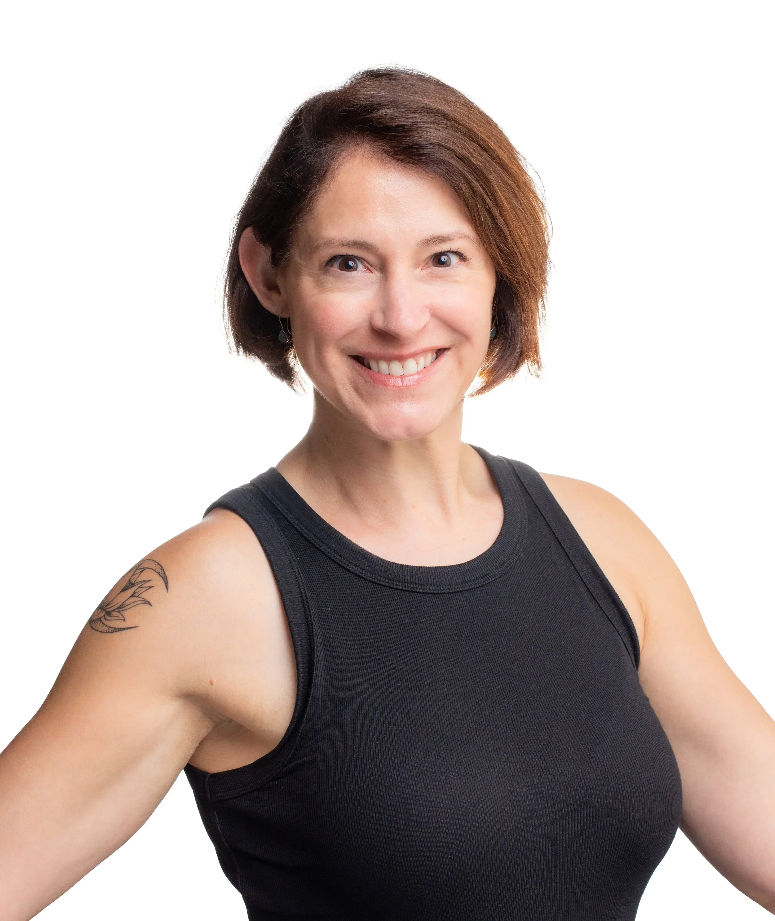 A smiling woman with short brown hair, wearing a black sleeveless top, posing with her arms slightly raised, against a white background.