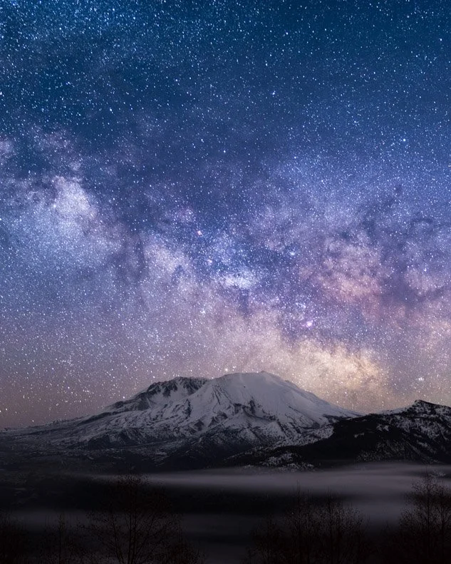 Snow-capped mountain under a starry night sky with visible Milky Way galaxy.