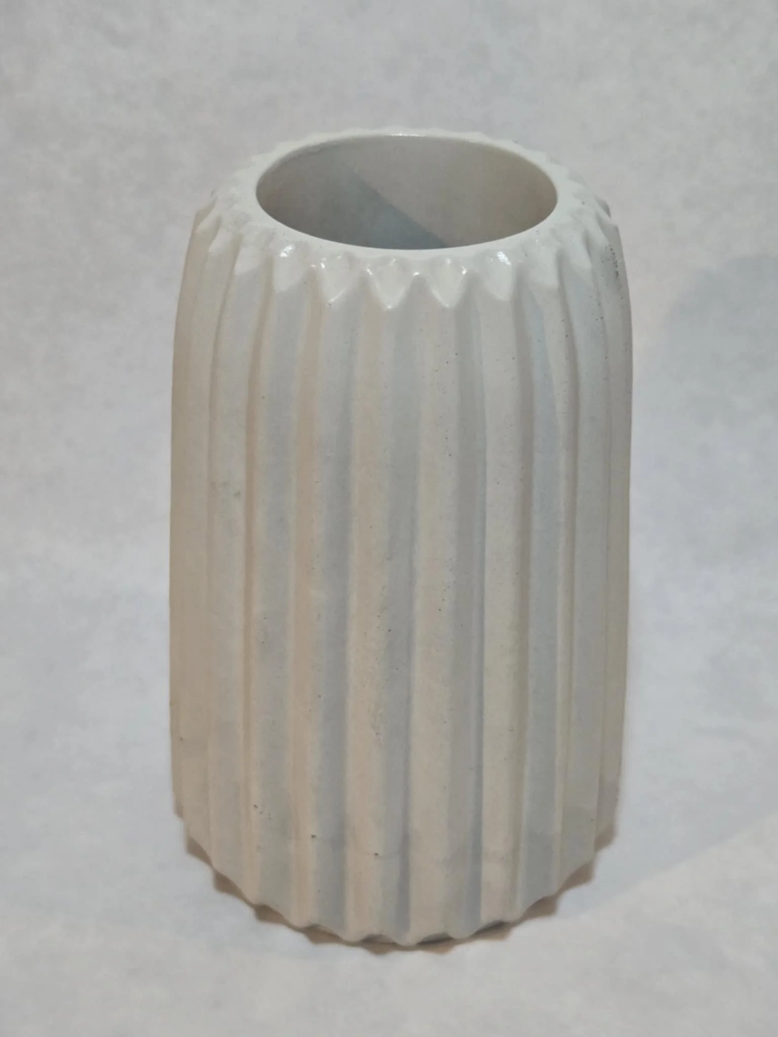 A white ceramic vase with vertical ridges.