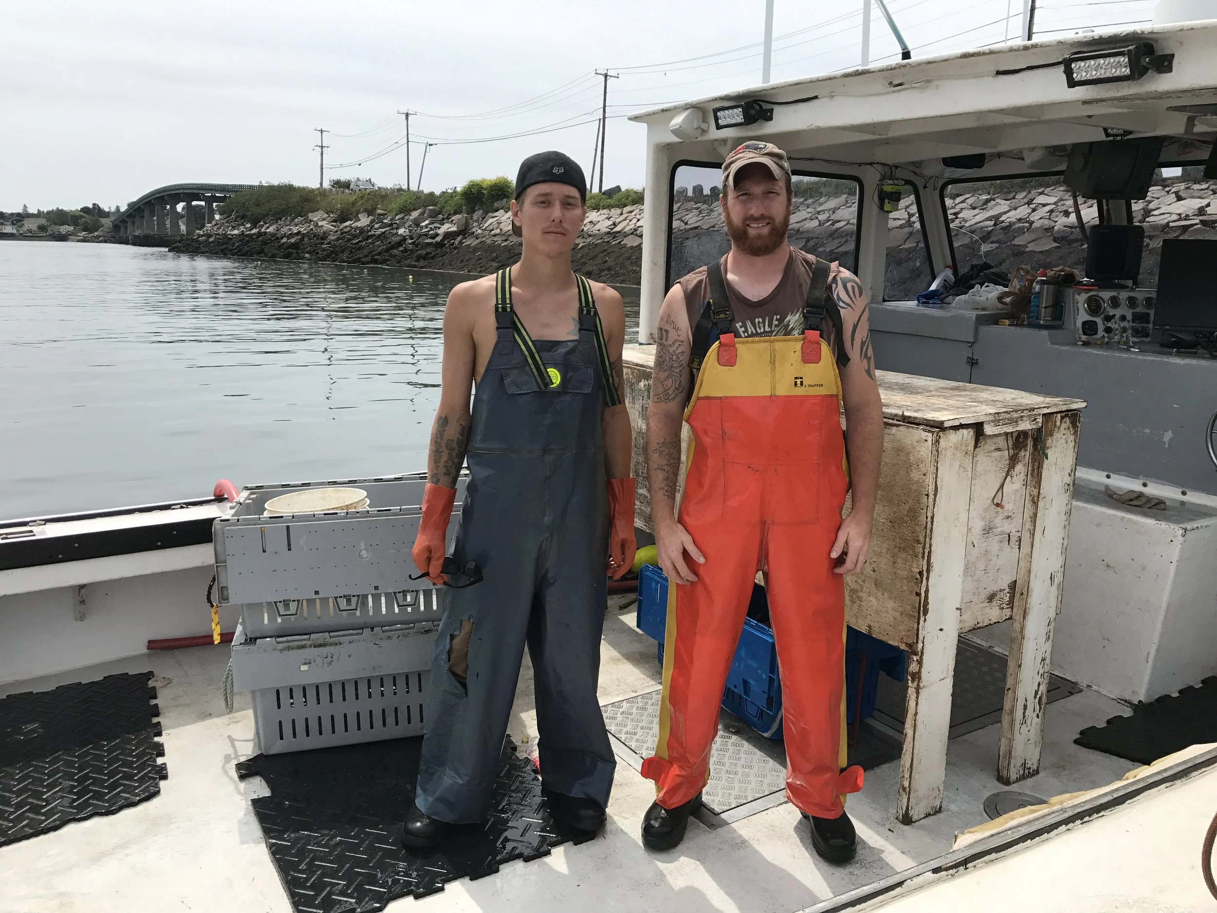 Two lobstermen from Lobster 207 standing on a boat posing for a photo.