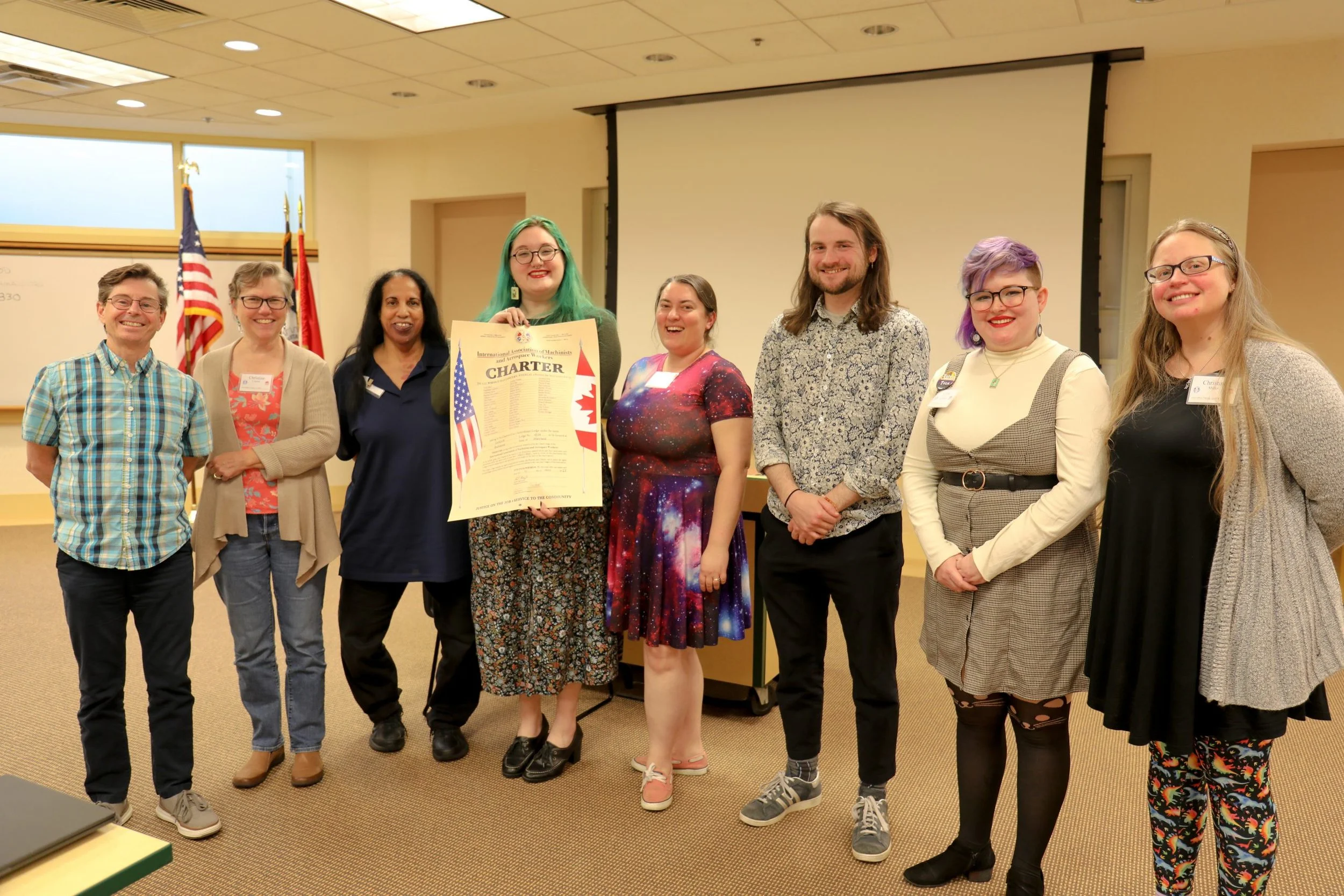 Eight members of the Local 4538 executive board pose with their local charter in a classroom at the W3 Center for Technology and Education.