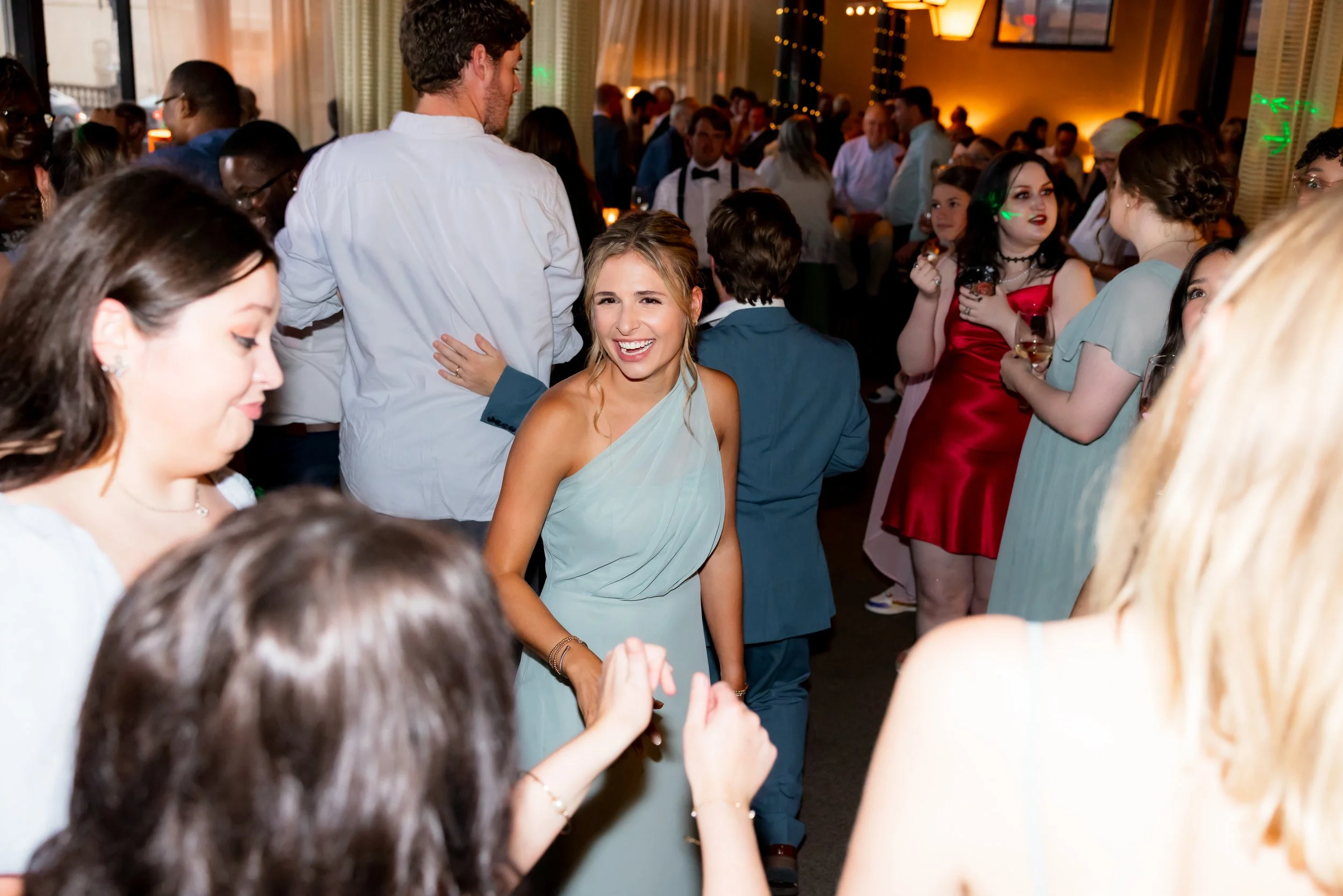 people dancing at a wedding with a girl in the center dancing and smiling