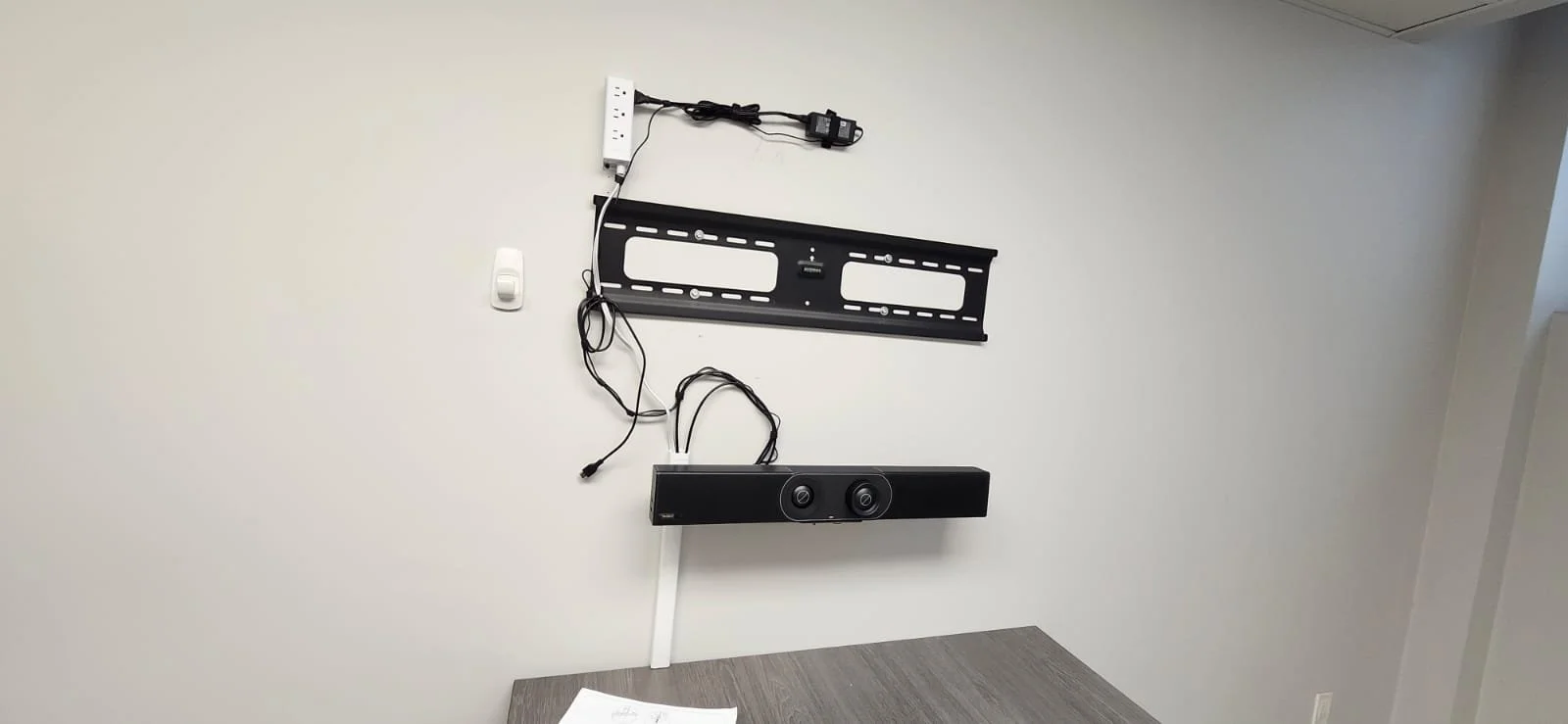 Unassembled home theater speaker and wall mount on a white wall.