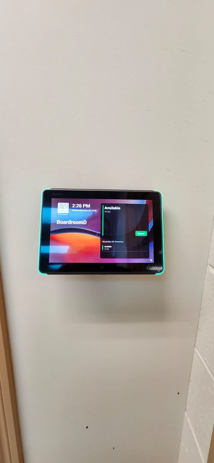 A wall-mounted digital display showing a meeting room reservation schedule with times and availability.