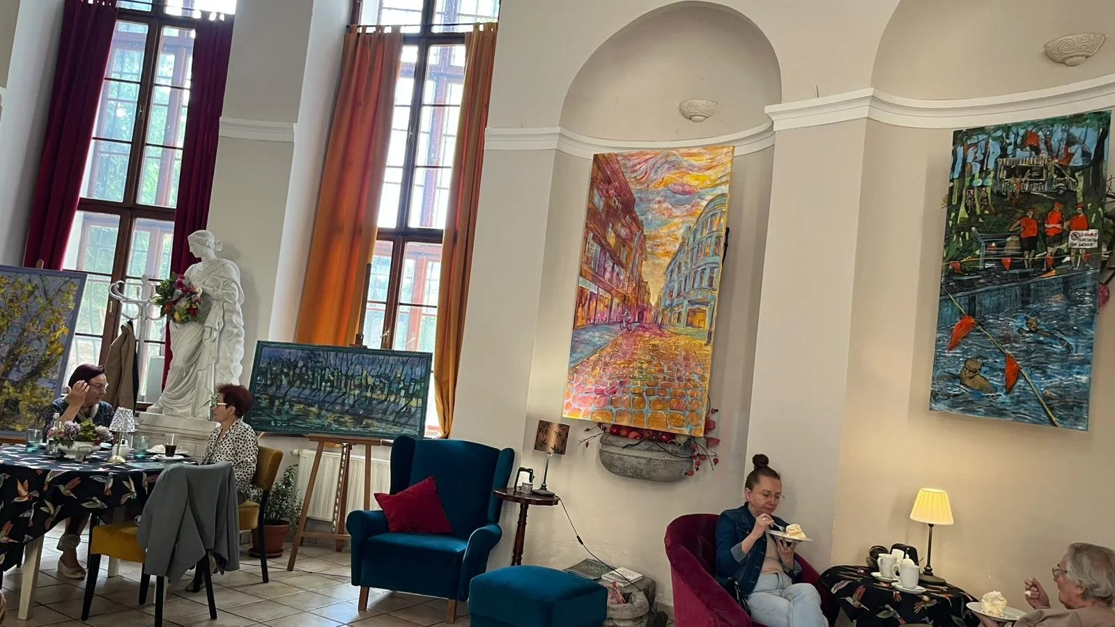 Art exhibition showing four mixed media paintings displayed on cafe wall