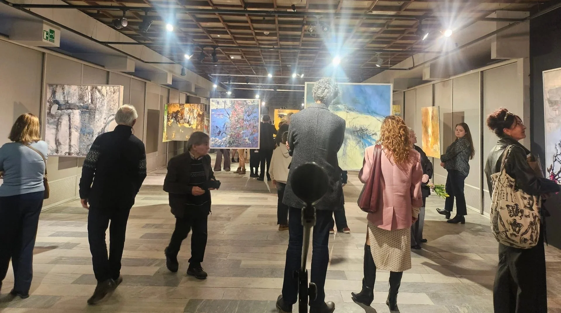 People walking through a gallery space and viewing contemporary paintings during cultural show
