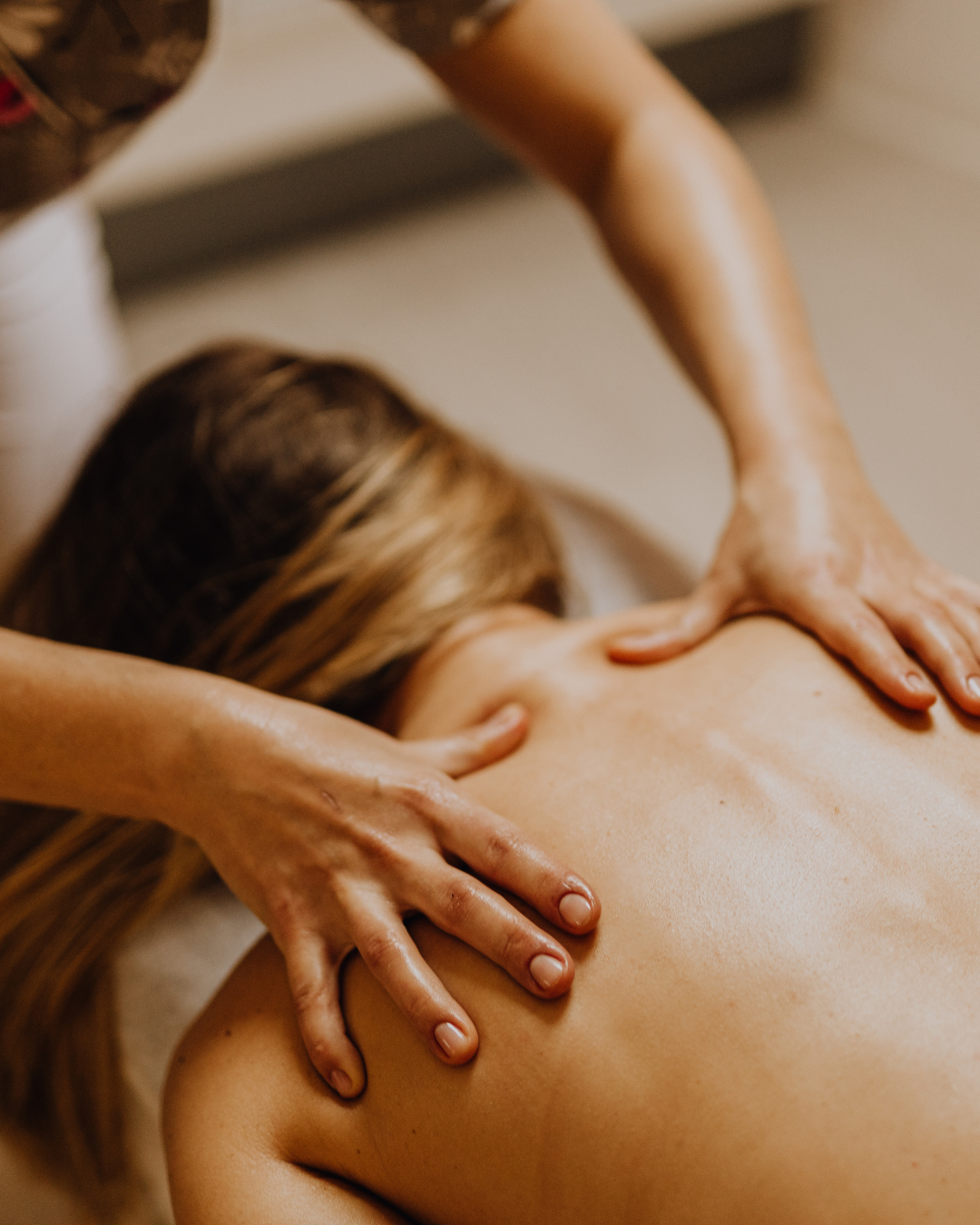 Une personne reçoit un massage sur le dos, allongée sur le ventre, avec les mains du masseur visibles appliquant une pression.