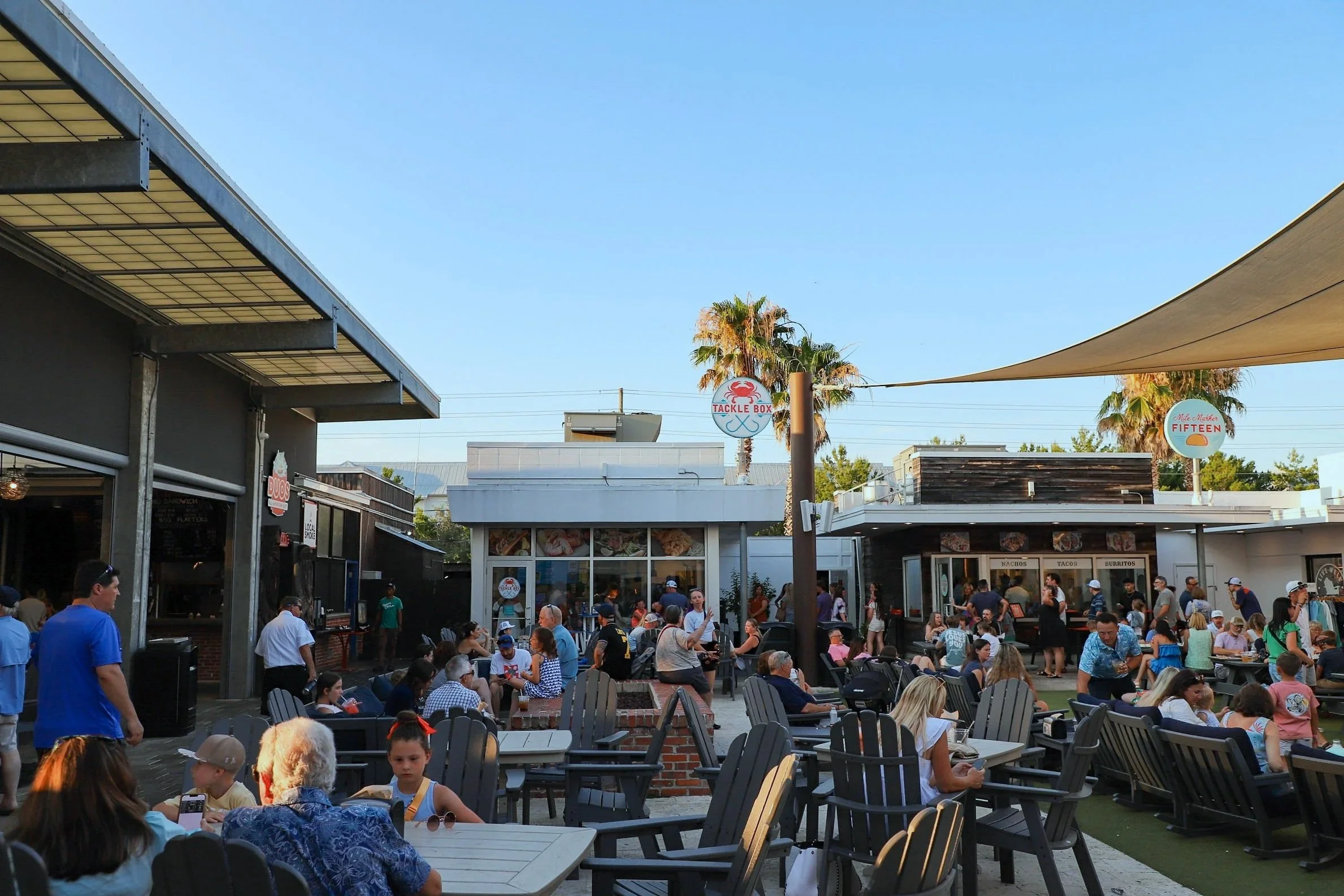 An outdoor dining and shopping area with many people. The Big Chill 30a