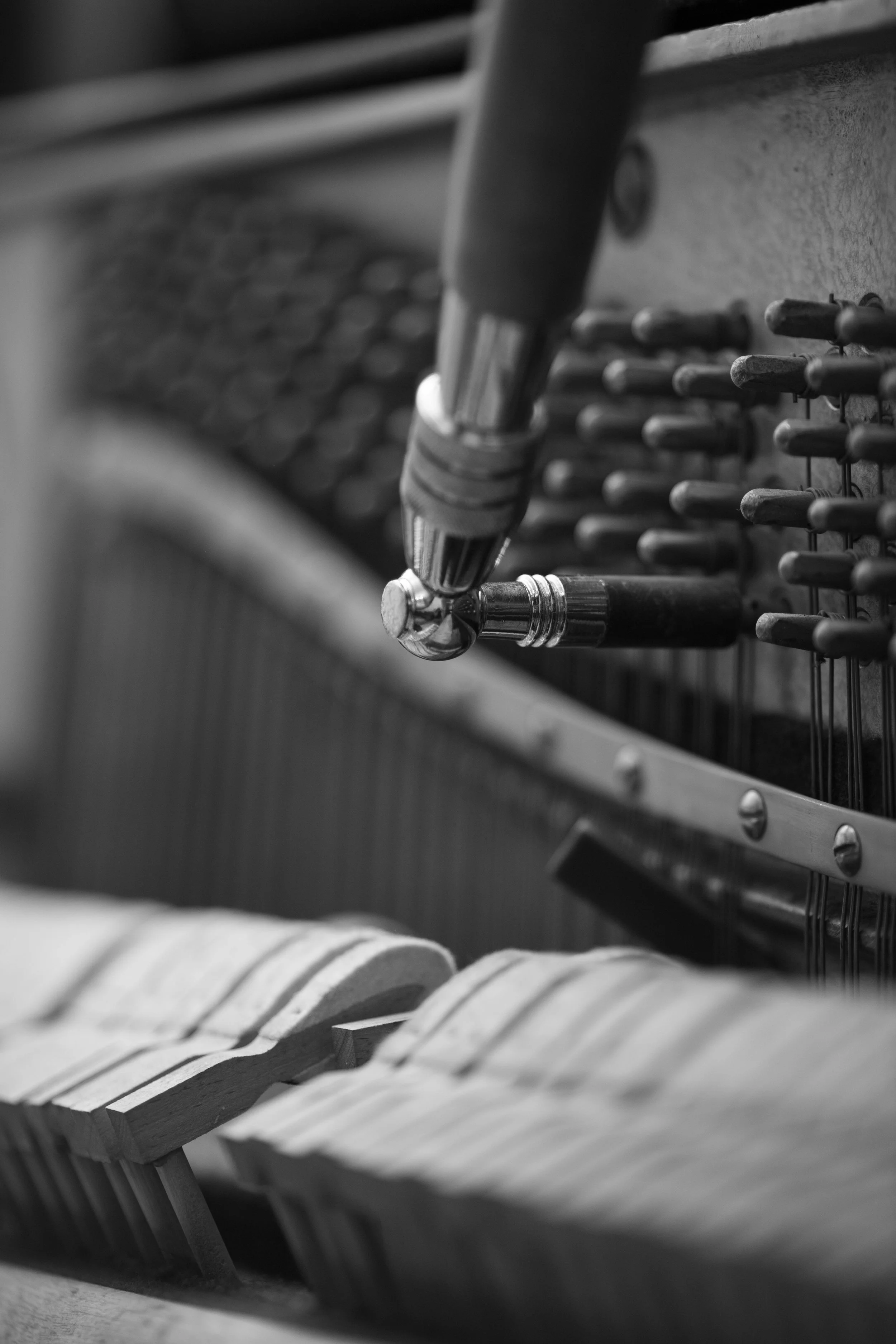 Close-up of a tuning hammer adjusting the tuning pins inside a piano