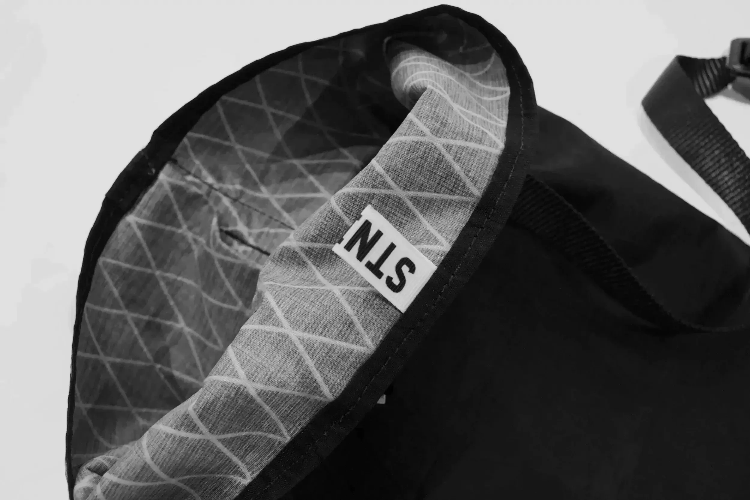 Close-up of a black backpack with gray interior lining and a white label that reads 'STH' inside