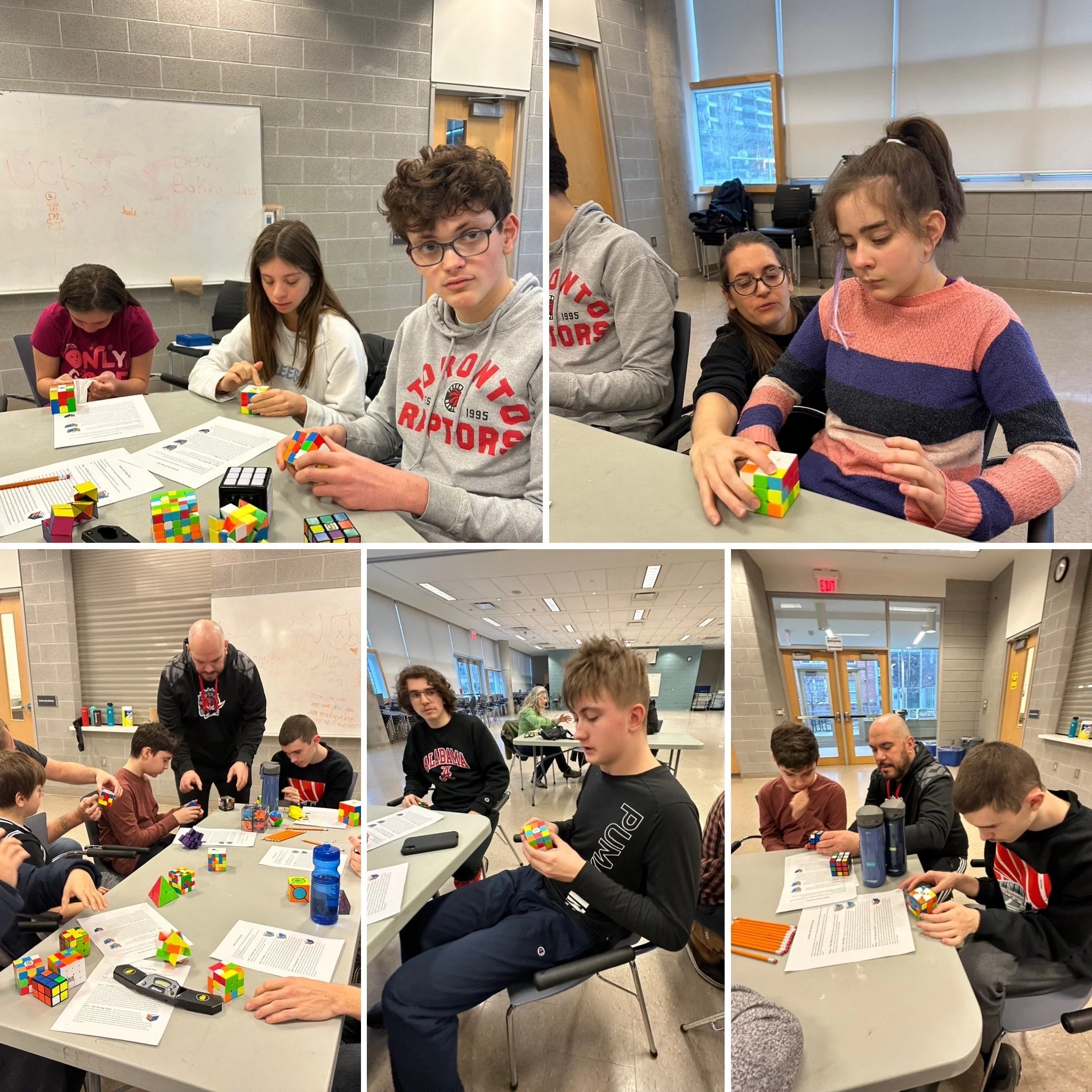 Students and adults in a classroom working on solving Rubik's cubes, with papers and notebooks on the tables.
