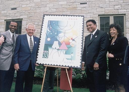 Dave Thomas, Mohammad Ali, and others standing with a US Commerative Stamp for Adoption