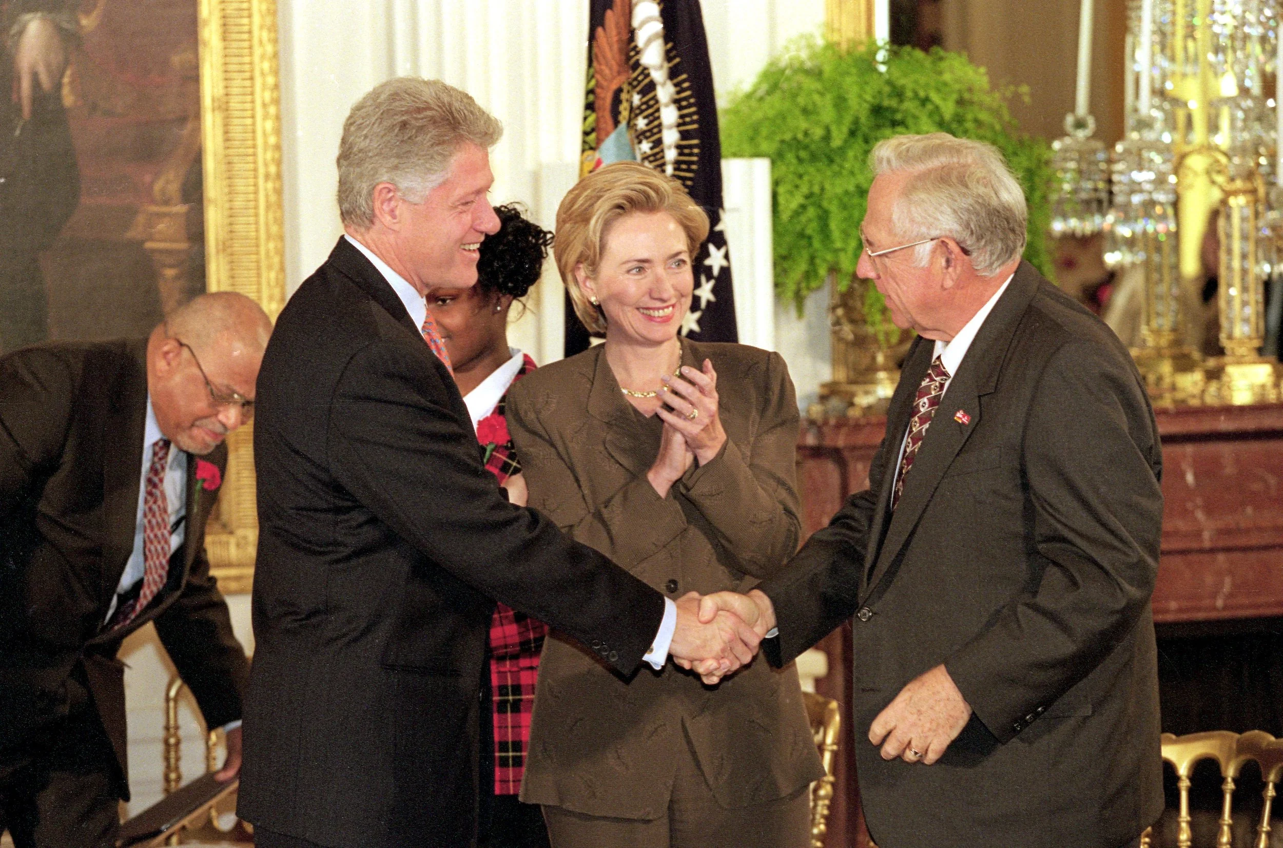 Dave Thomas, Founder of Wendy's, shaking hands with President Bill Clinton at an adoption event at the White House, with First Lady Hillary Clinton