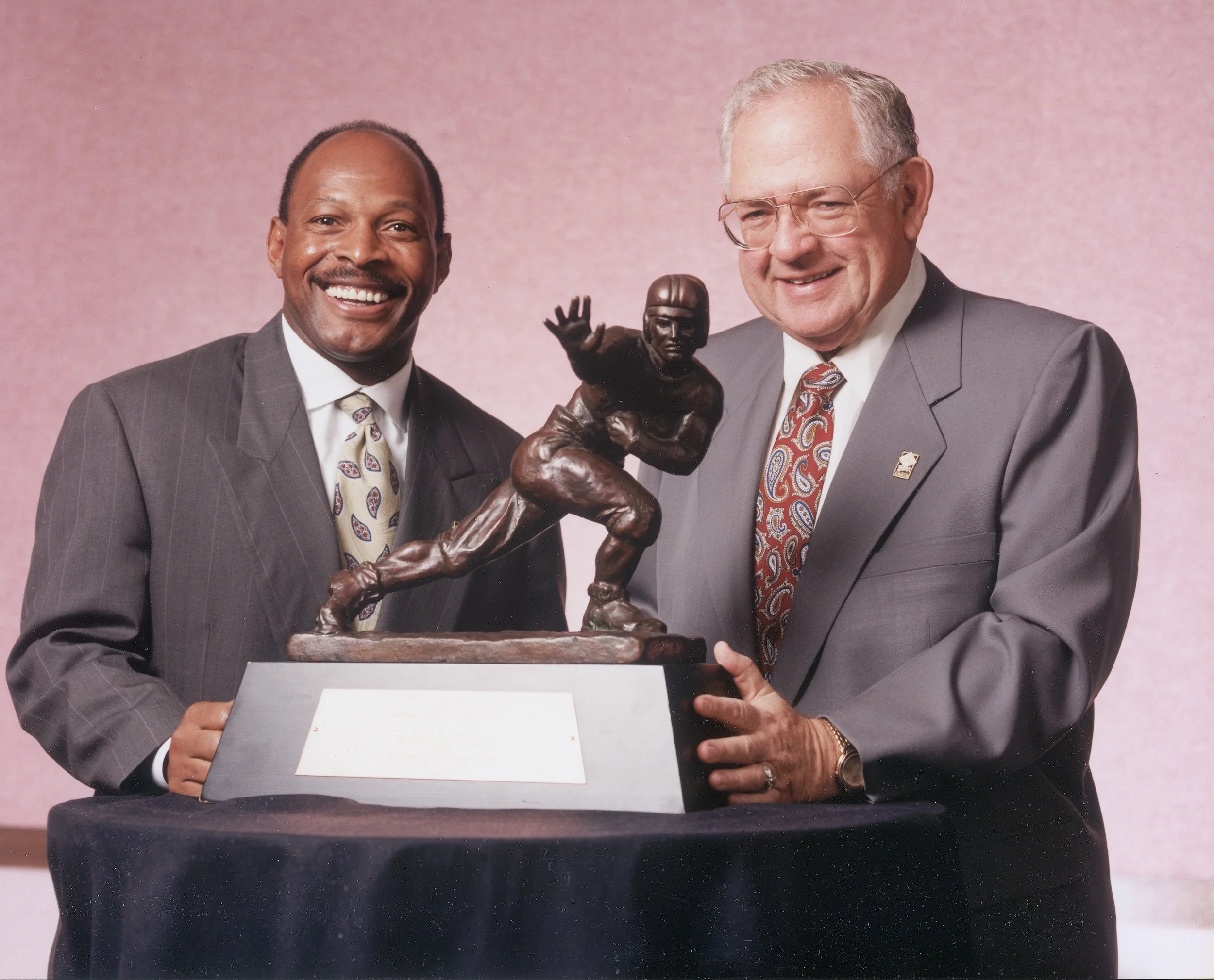 Two-time Heisman winner, Archie Griffin, posing with Dave Thomas, Founder of Wendy's, with the Heisman Trophy