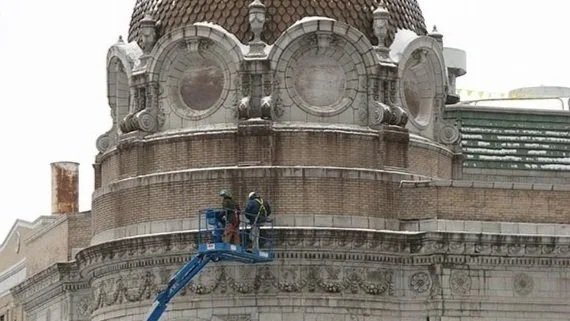 Two workers on a  lift inspecting the cupola of the historic Main Street.