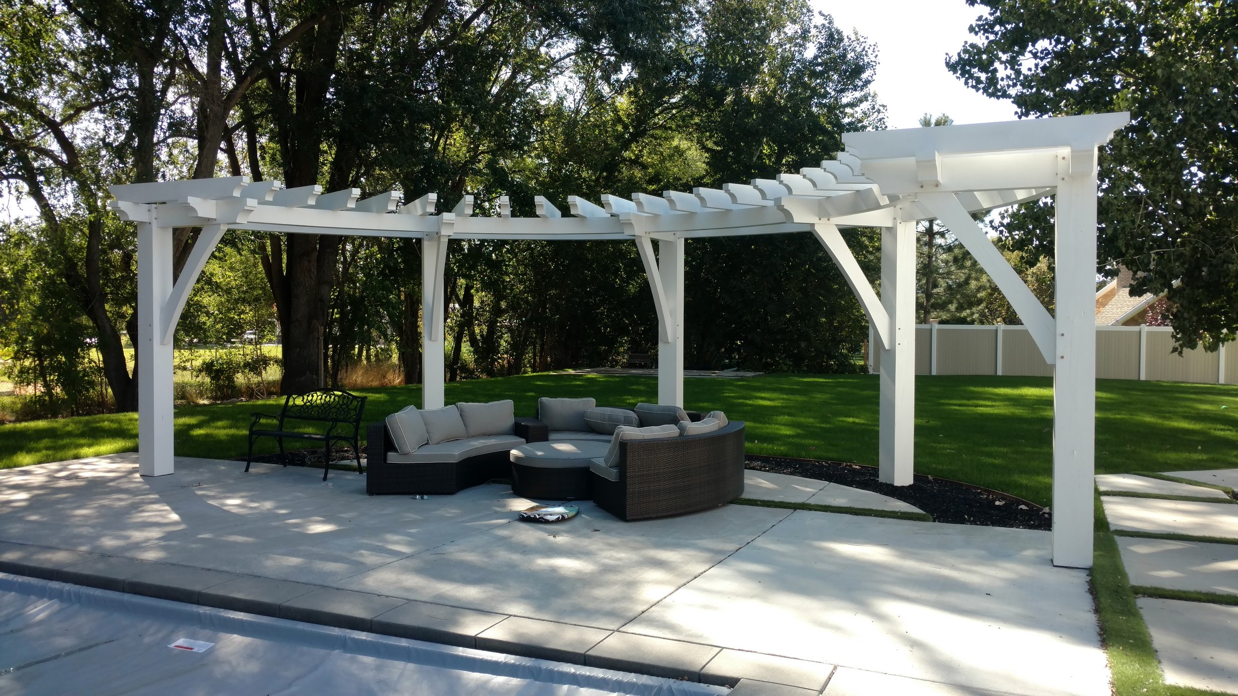 Modern white backyard pergola install shading the pool and patio. 