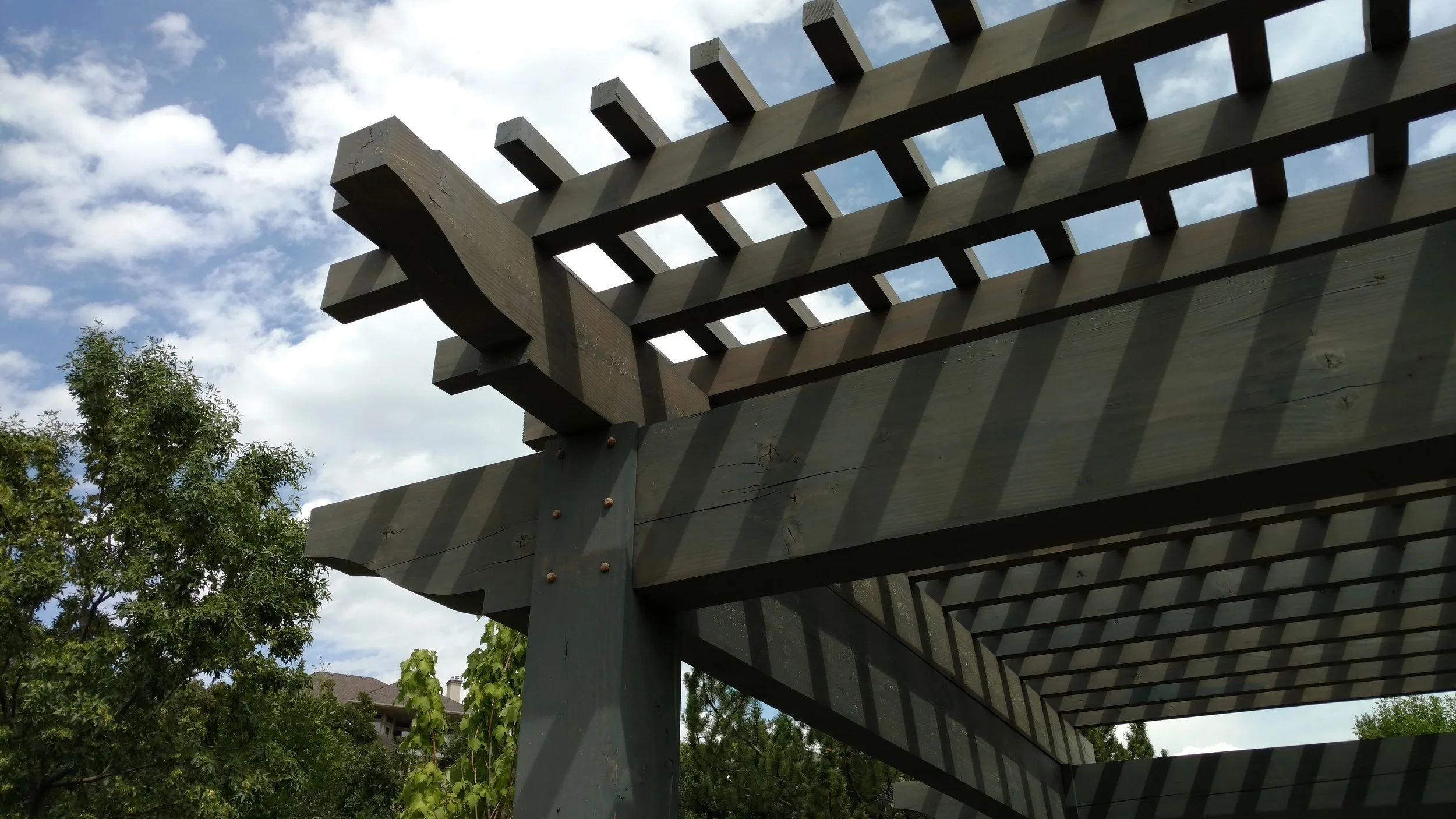 Layered timber pergola shading a backyard sitting area and hot tub as a custom build for outdoor living. 