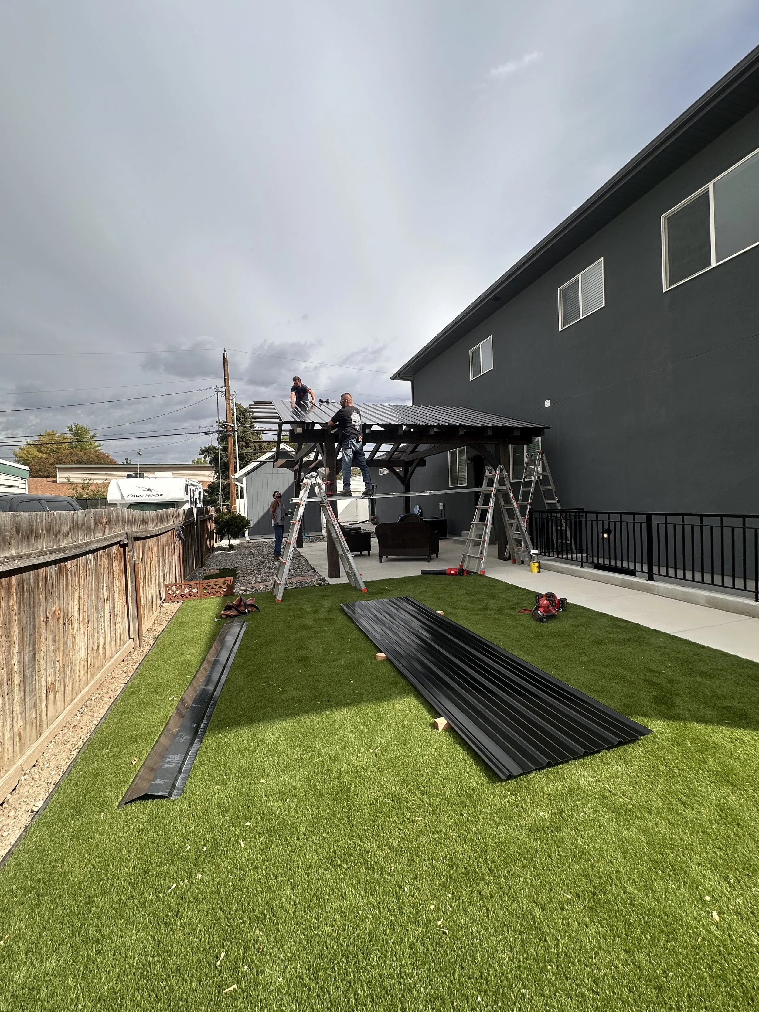 Our team installing a modern backyard pergola design with a metal roof.  