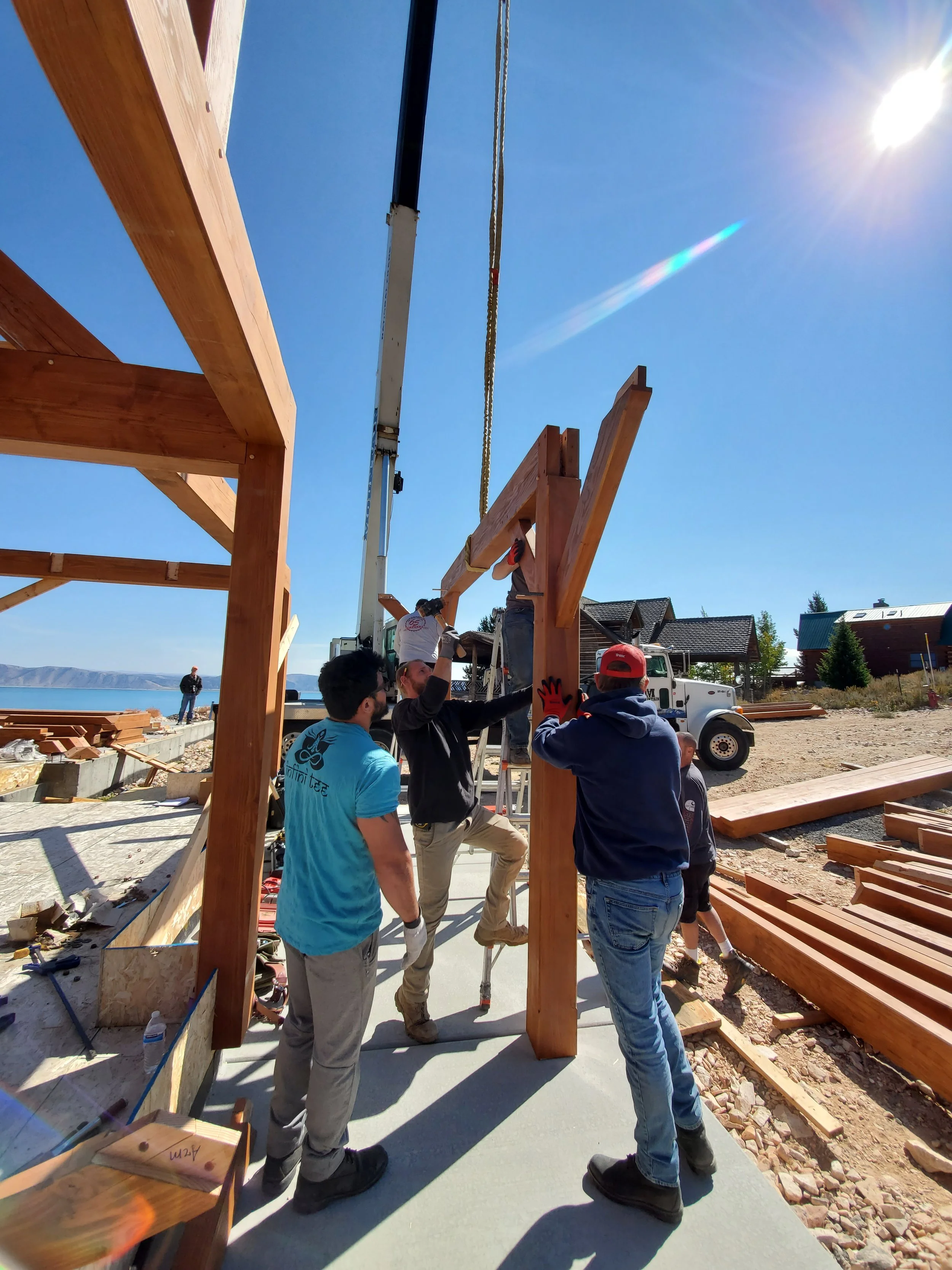 Group of workers assembling a wooden structure outdoors on a sunny day.