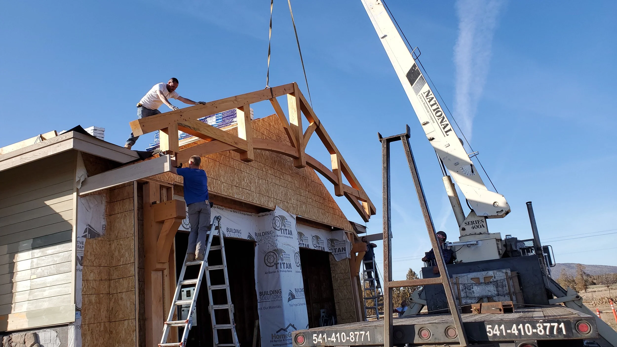 Our team installing a heavy timber outdoor beam on the front of the house under construction. 