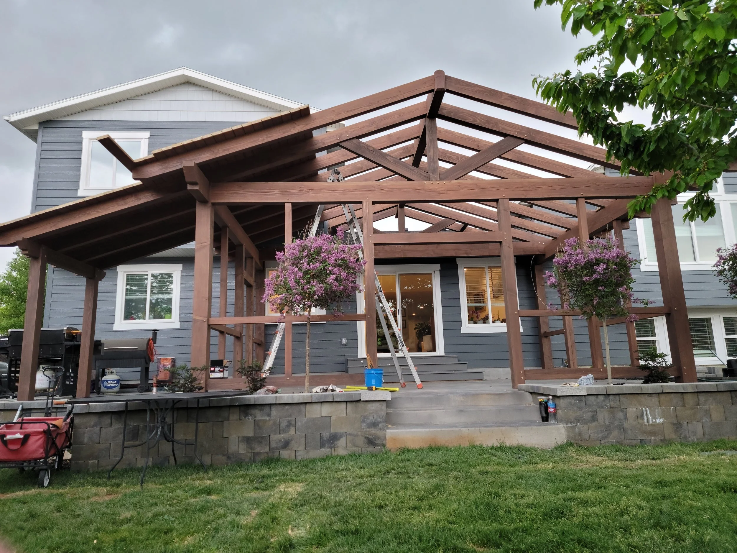 A timber frame pergola, under construction,  in the framing stages while being installed. 