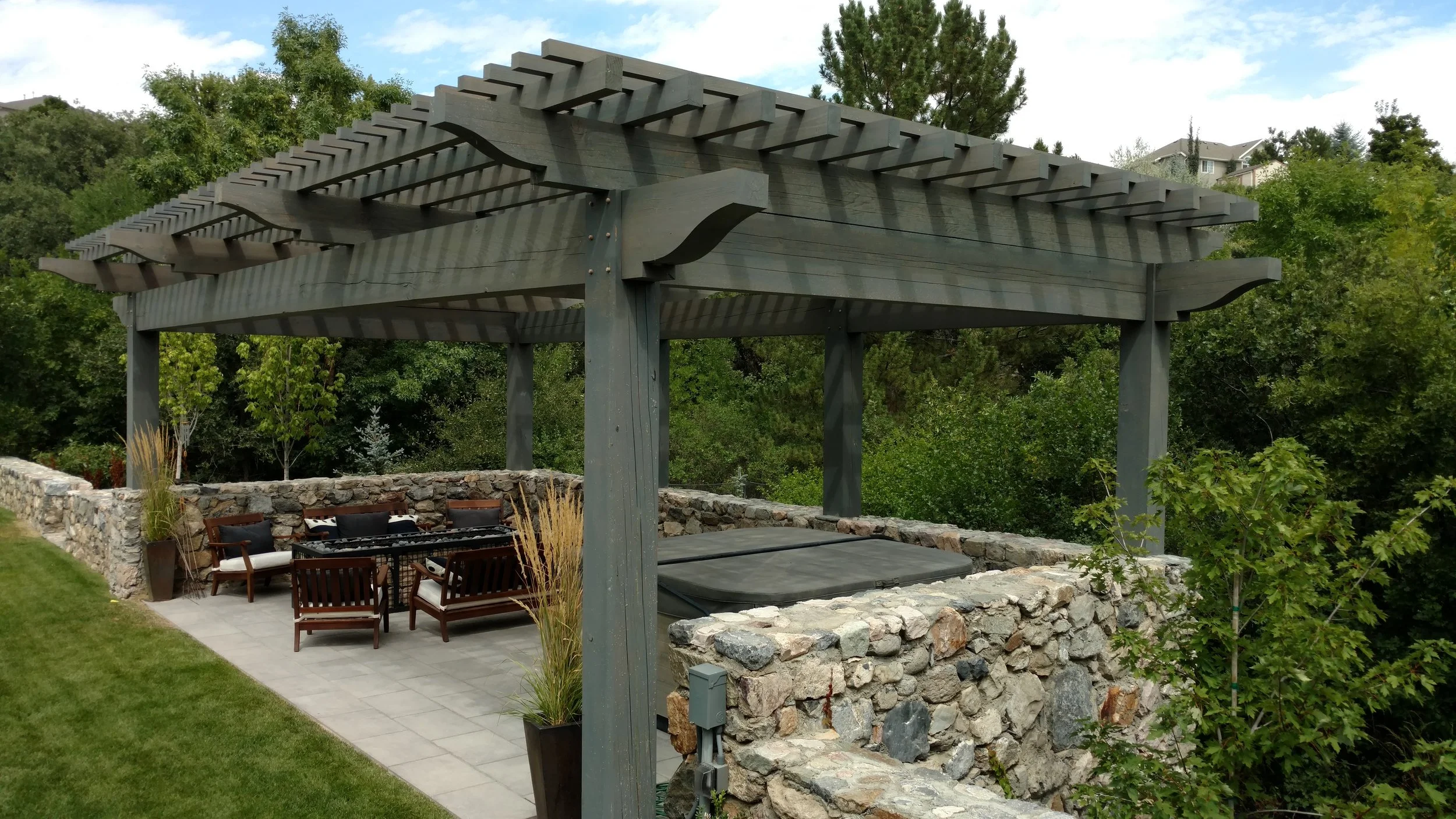 Layered timber pergola shading a backyard sitting area and hot tub as a custom build for outdoor living. 