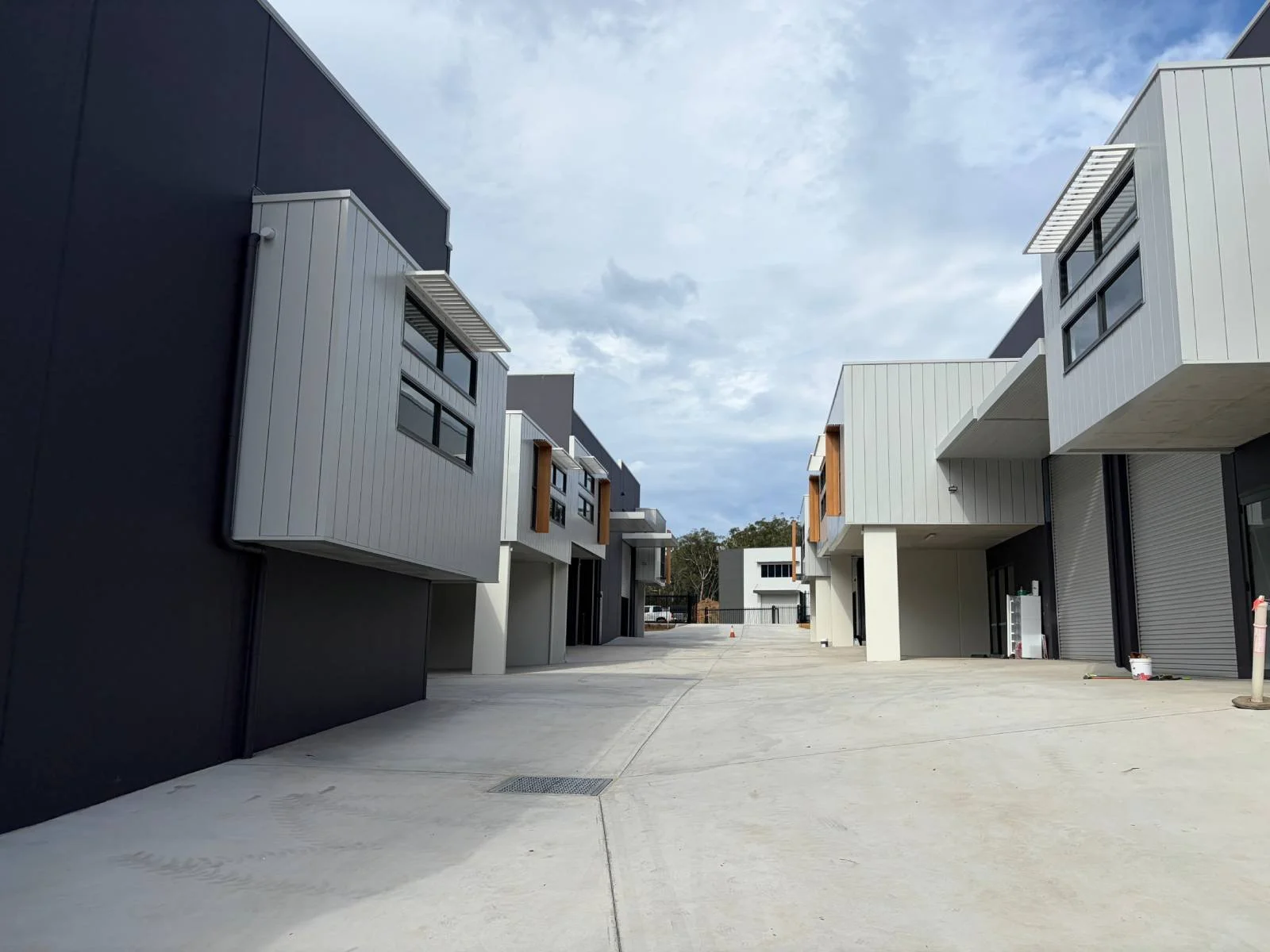 View of modern apartment complex with parked cars, multiple types of exterior walls, and a cloudy sky.