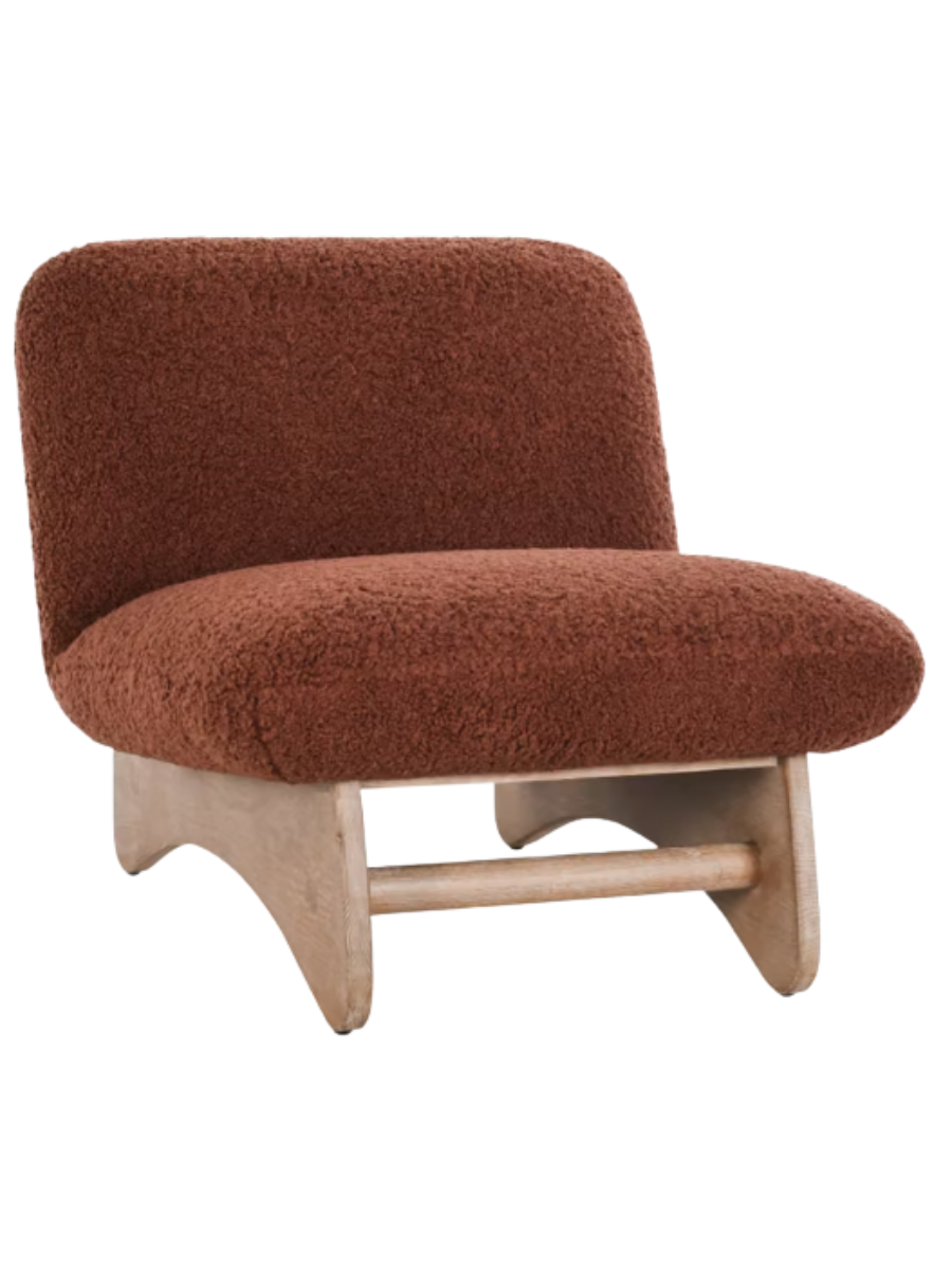 Modern armless accent chair upholstered in rust-colored bouclé fabric with a curved backrest, wide cushioned seat, and natural wood base.