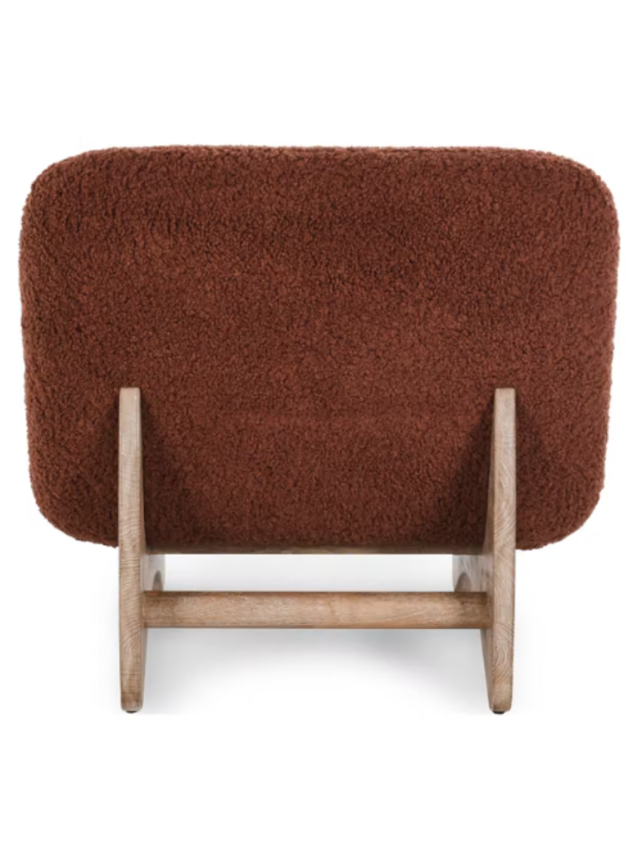 back view of Modern armless accent chair upholstered in rust-colored bouclé fabric with a curved backrest, wide cushioned seat, and natural wood base.