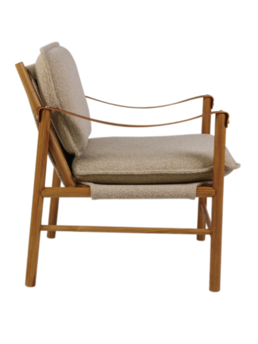 Mid-century modern accent chair with beige upholstered cushions, a natural rubberwood frame, and cognac leather sling armrests with brass accents.