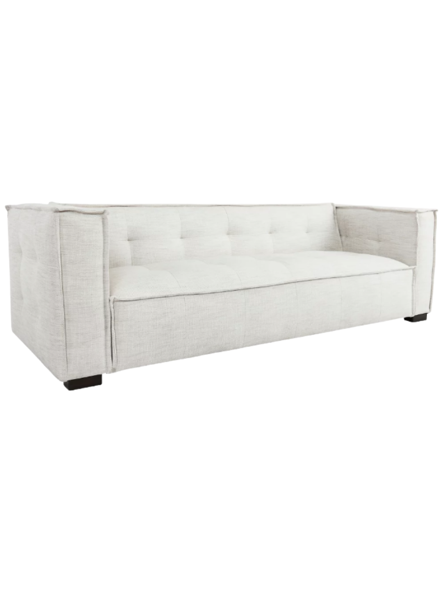 Modern ivory textured fabric sofa featuring subtle tufting along the backrest and bench seat, wide square arms, clean piping details, and short dark wood legs.