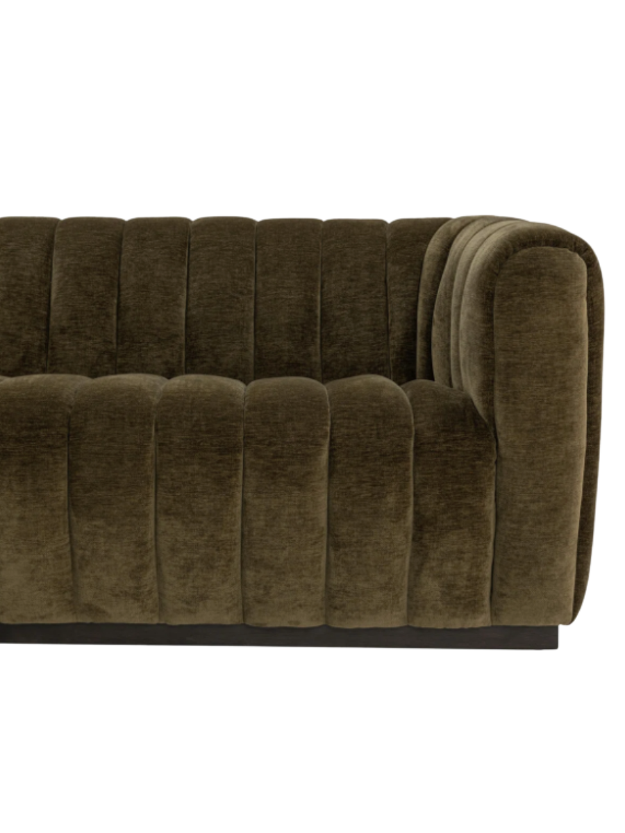Modern olive green velvet sofa featuring vertical channel tufting, a low-profile silhouette, rounded arms, and a dark recessed base.