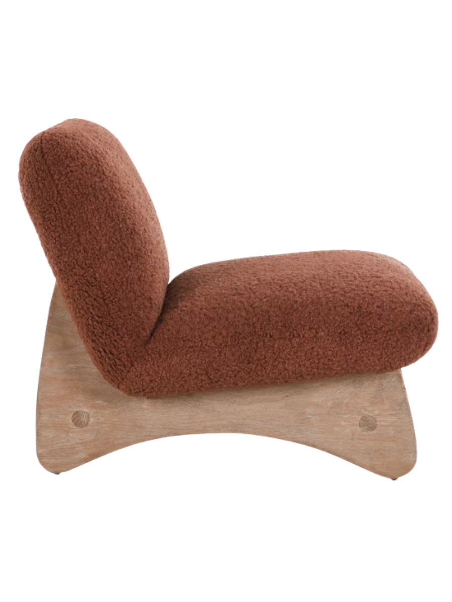 Side view of Modern armless accent chair upholstered in rust-colored bouclé fabric with a curved backrest, wide cushioned seat, and natural wood base.
