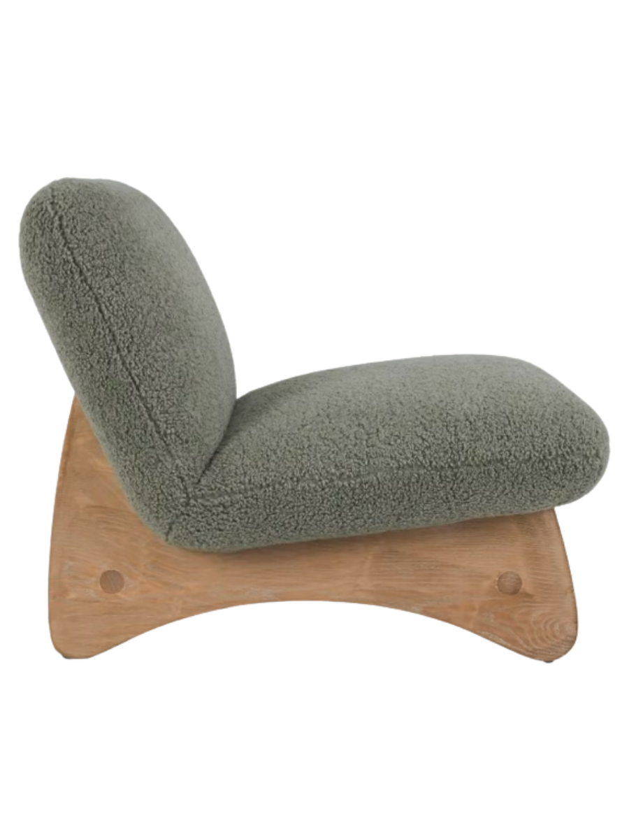 Side view of Modern armless accent chair upholstered in sage green bouclé fabric with a curved backrest, wide cushioned seat, and natural wood base.