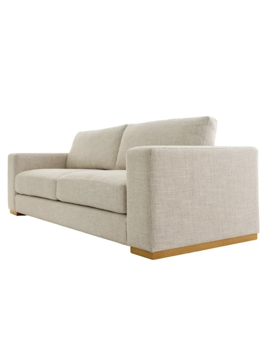 Modern two-seat sofa upholstered in light beige textured fabric, featuring clean lines, wide square arms, plush seat and back cushions, and a natural wood base.