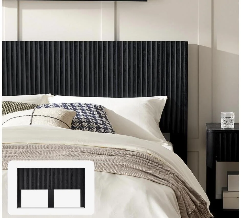 A bedroom with a black textured headboard, white bedding, decorative pillows, and a black nightstand with a glass of water.