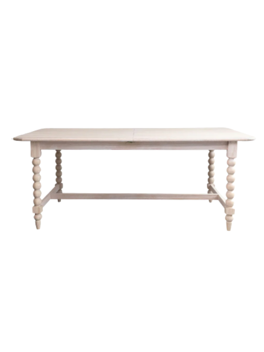 Traditional rectangular dining table in a light natural wood finish, featuring decorative turned spindle legs with rounded ball details, a trestle base, and a spacious tabletop.