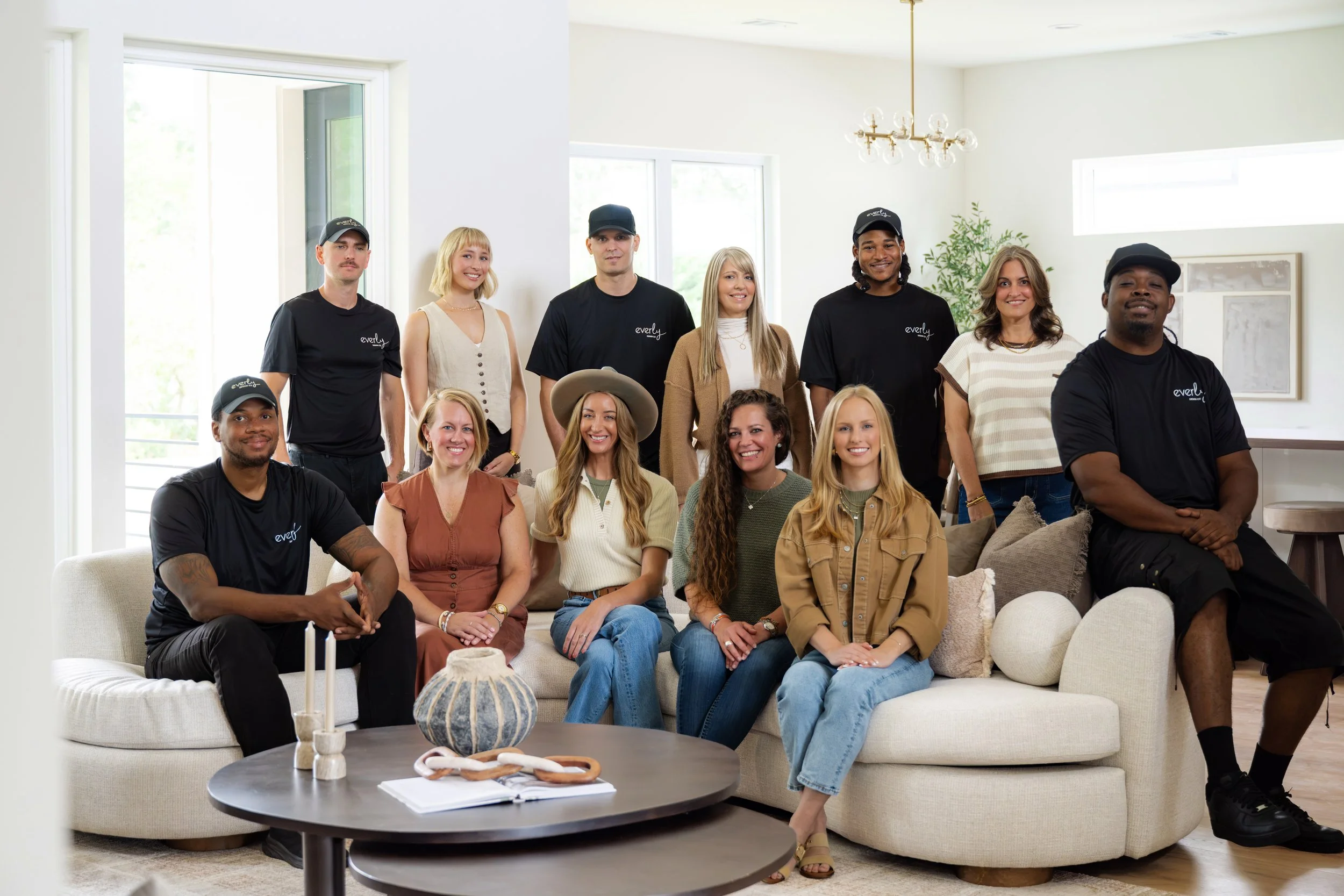 Group of diverse people sitting and standing in a bright, modern living room with white walls and large windows