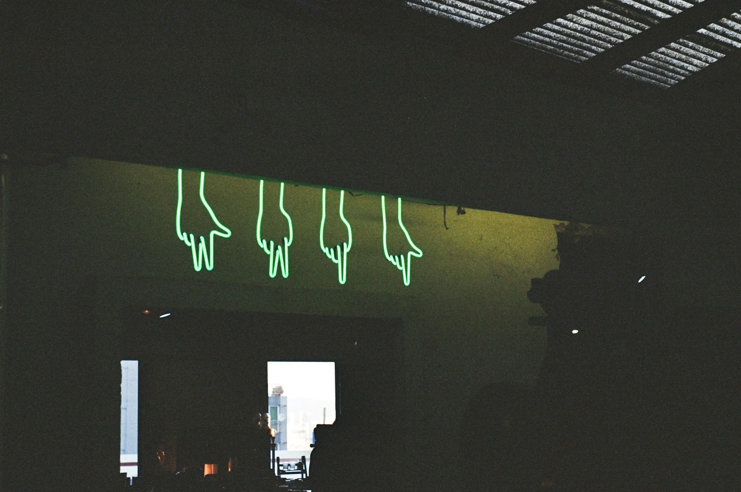 Neon sign displaying the words "four fingers" in bright colors against a dark background.