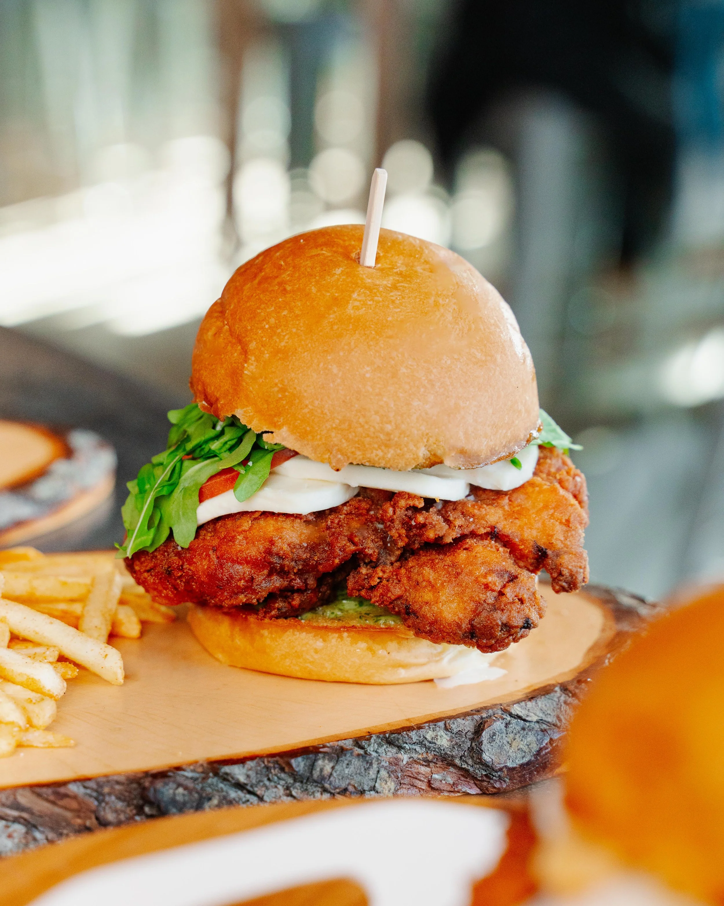 Not Your Mamala's Chicken Sandwich on wooden tray and accompied with fries