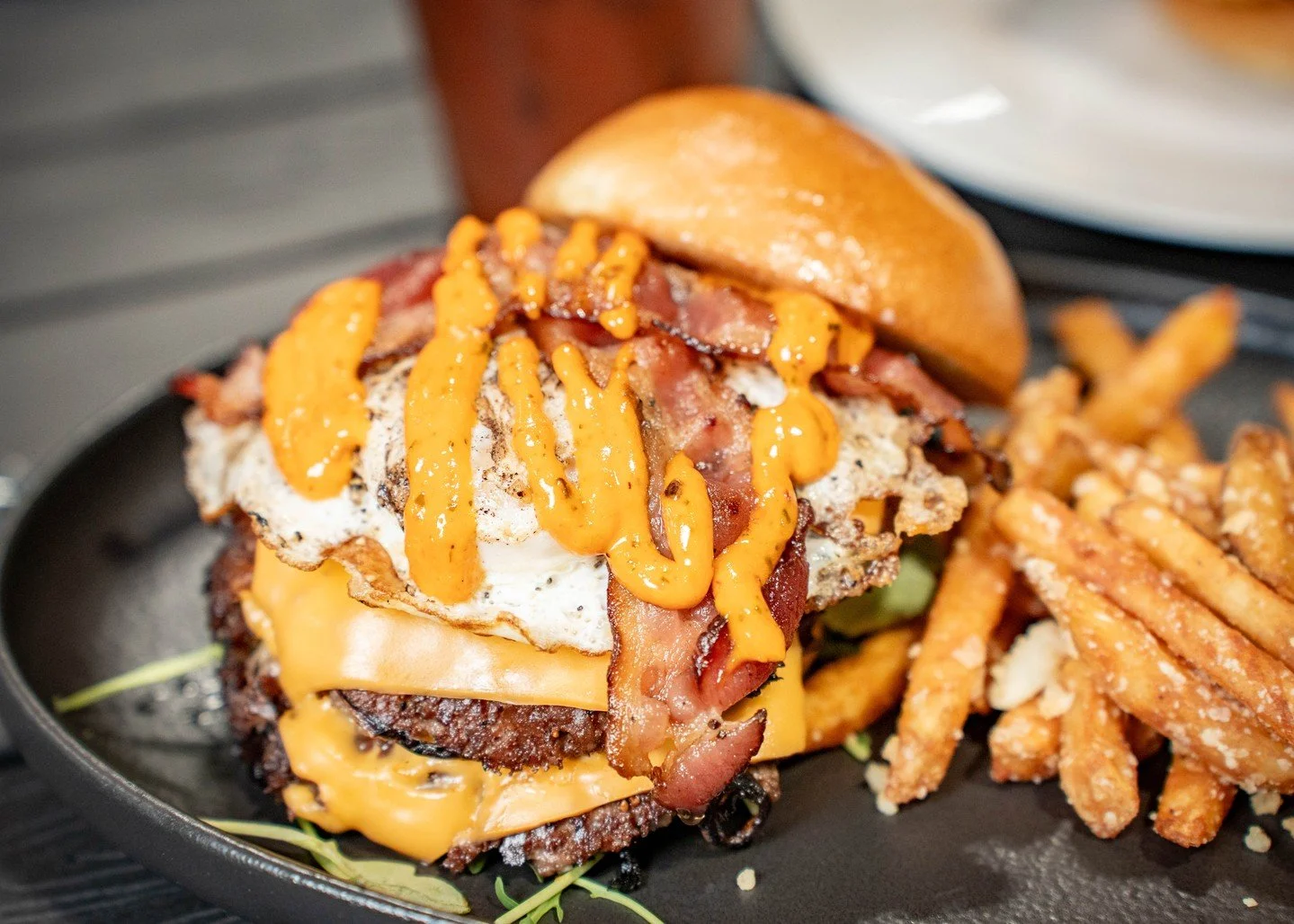 Who says you have to choose between breakfast and a burger? 🍳🍔

Two juicy patties, melted cheese, crispy bacon, a fried egg, and a generous drizzle of sauce, all stacked between a toasted bun. Add a side of fries, and you've got a breakfast worth g