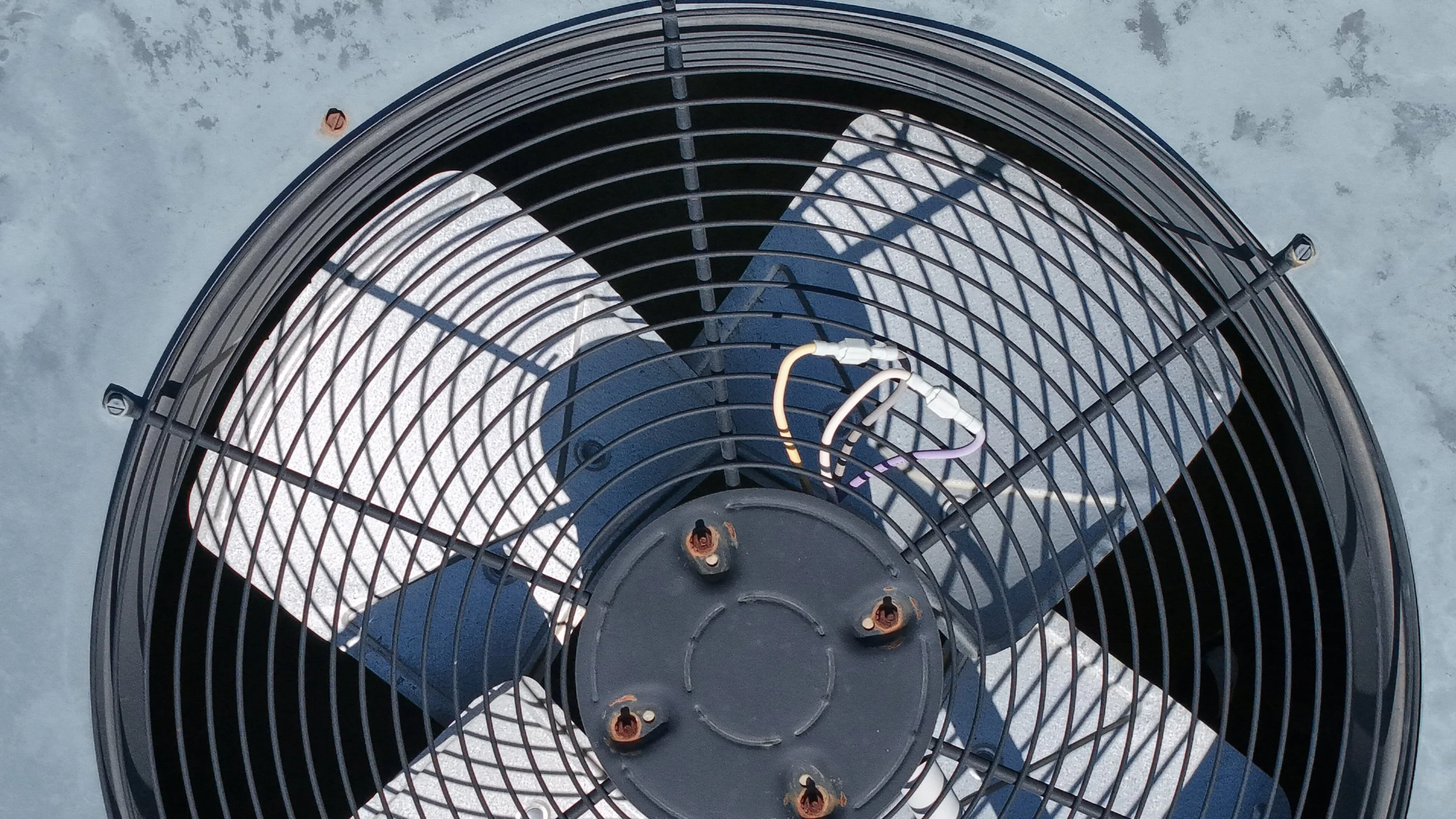 Top view of an industrial fan with metal grilles and visible electrical wiring.