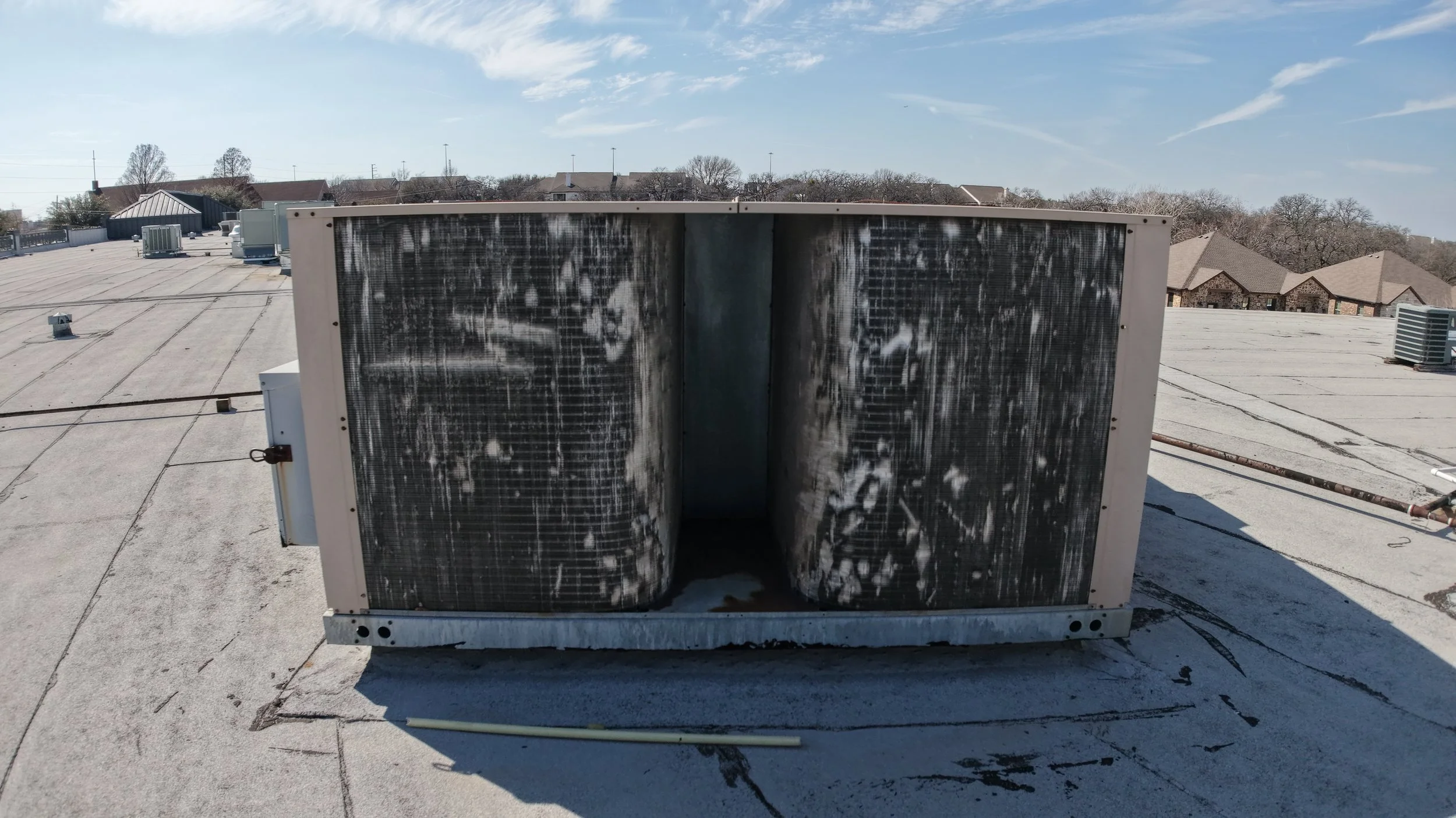Rooftop air conditioning unit on a flat roof with clear sky in the background.