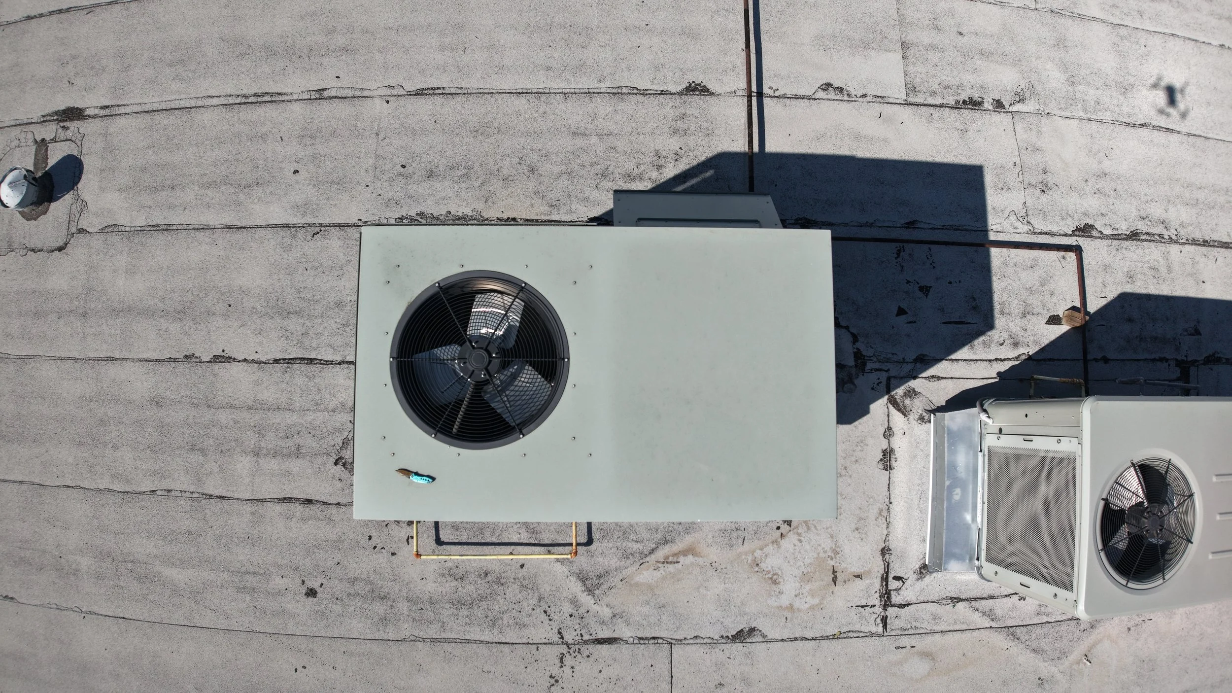 Overhead view of rooftop air conditioning units on a flat roof.