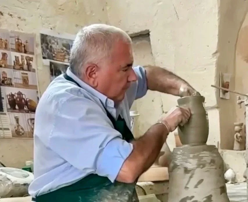 A man with gray hair working on a pottery piece in a workshop on the wheel, handmade.