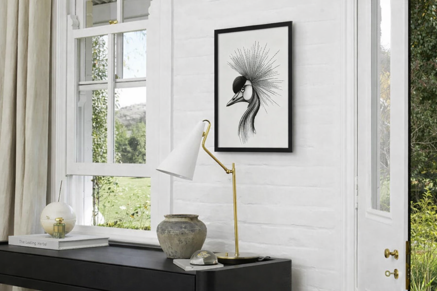 Interior of a room with large windows, white brick wall, black console table, decorative lamp, pottery vase, and black and white framed artwork of a stylized bird with a spiky crest.