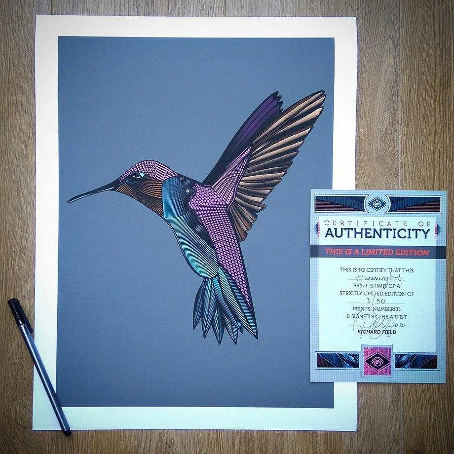 Colorful illustration of a hummingbird with detailed feathers, placed on a gray background with a pen nearby and a certificate of authenticity next to it.