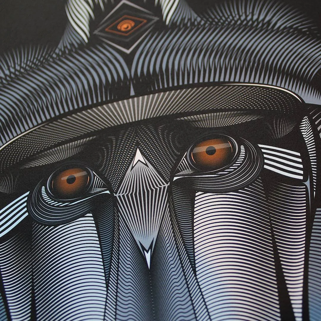 Close-up of an abstract, geometric design featuring a stylized face with orange eyes, intricate black and white line patterns, and a shield-like shape above the face.