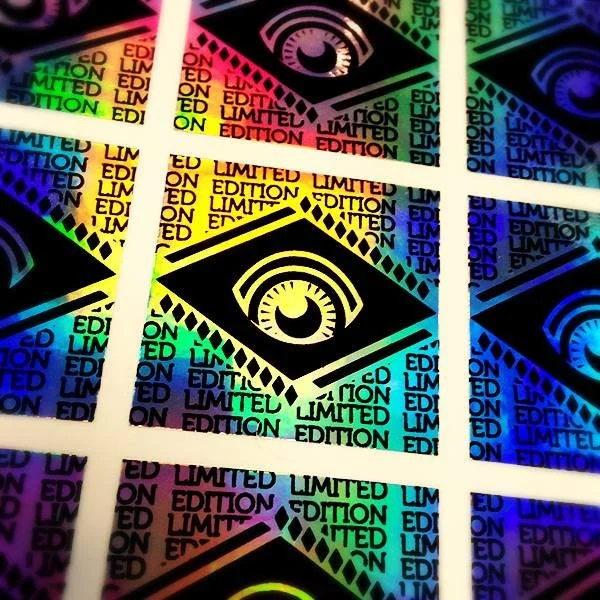 Close-up of holographic stickers with a stylized eye logo and the words 'Limited Edition' repeated in colorful text.