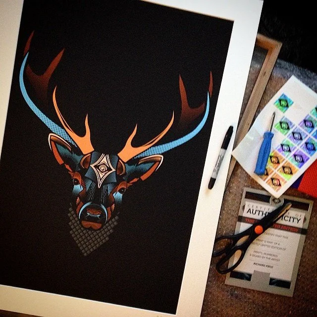 Colorful geometric deer head artwork on black background surrounded by art supplies, including scissors, markers, and watercolor paints.